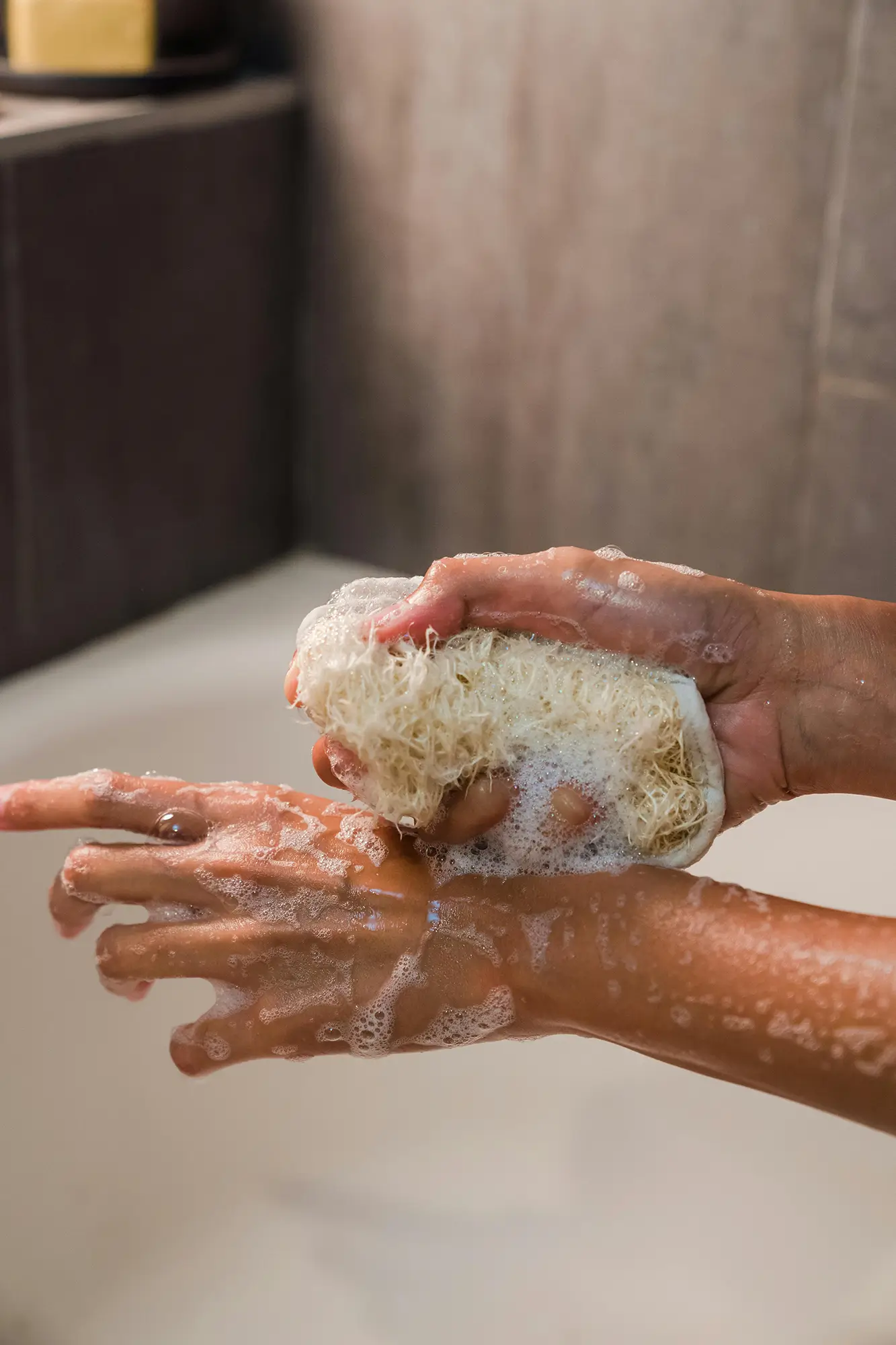 Feminine pair of hands washing with a sudsy natural loofah