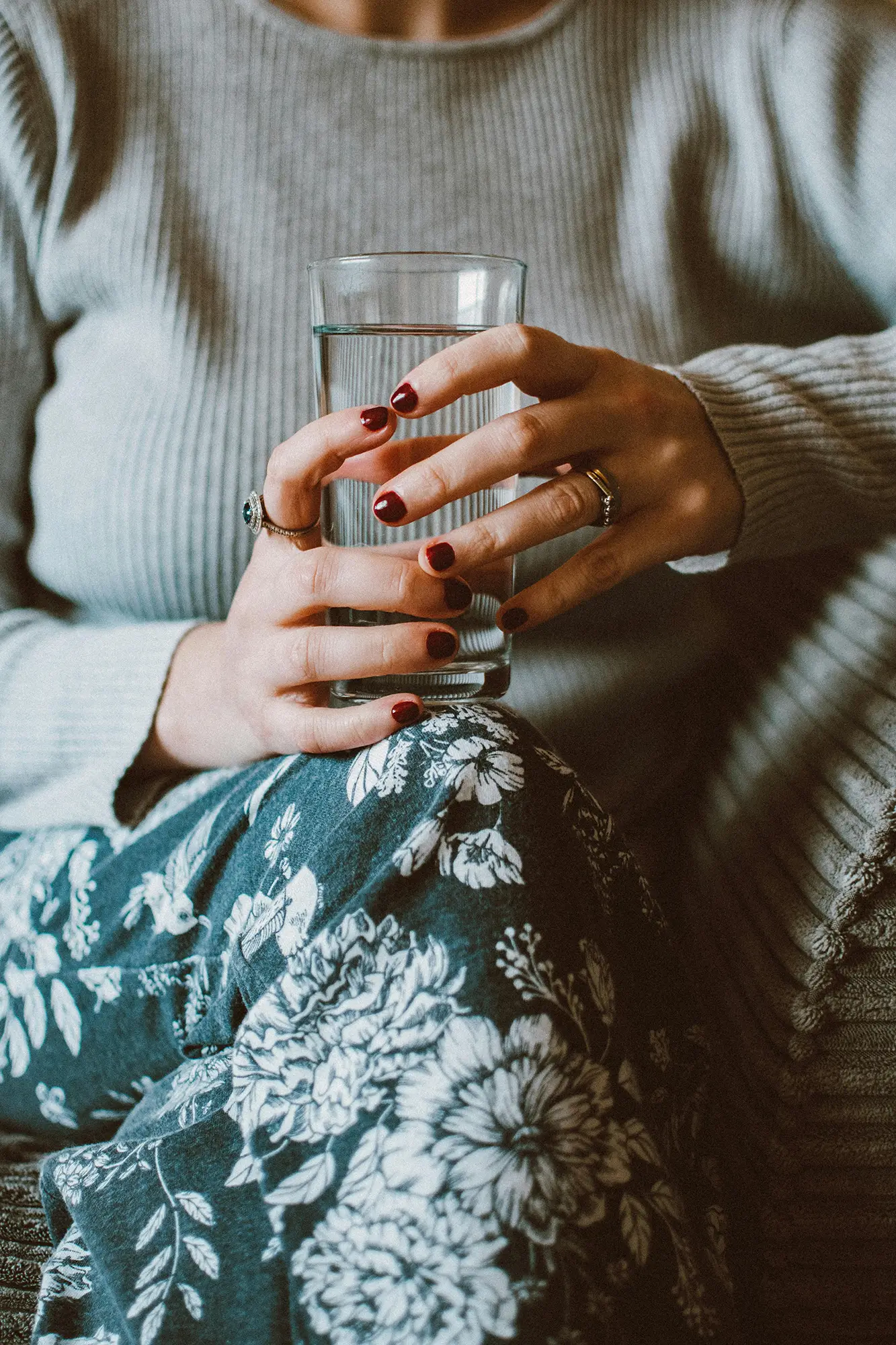 Closeup of a seated person resting a full glass of water on their knee
