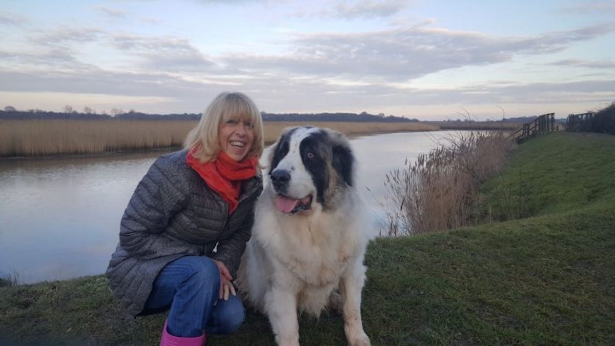 A woman and a dog posing for the camera by a riverside