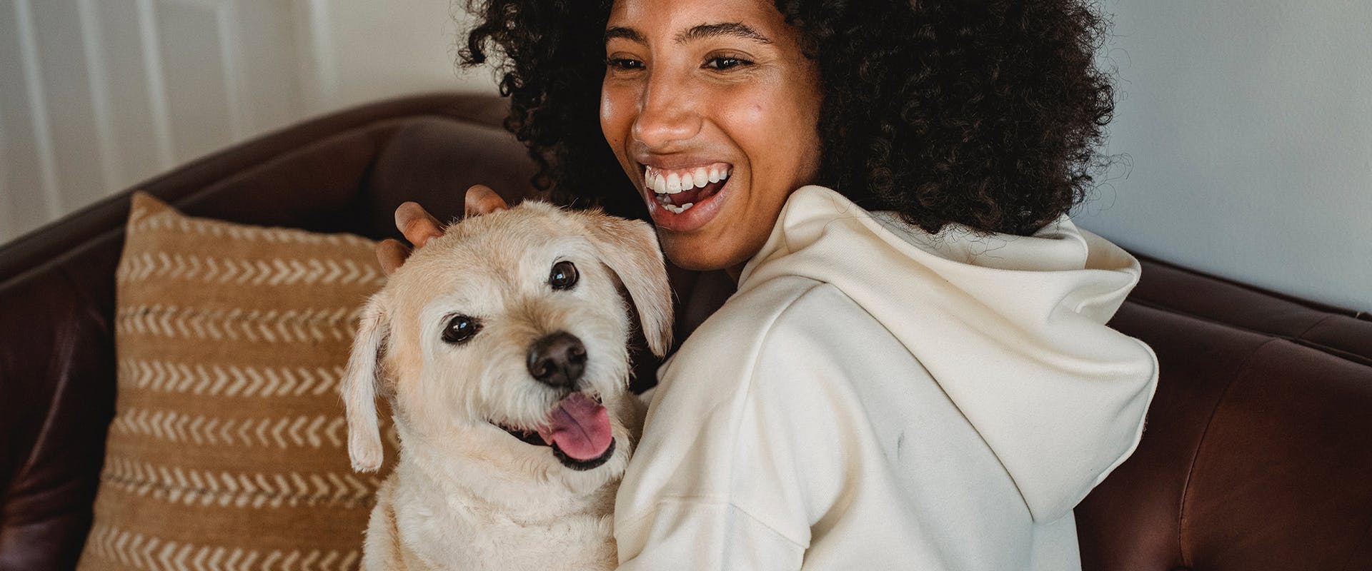A woman laughing while holding a dog