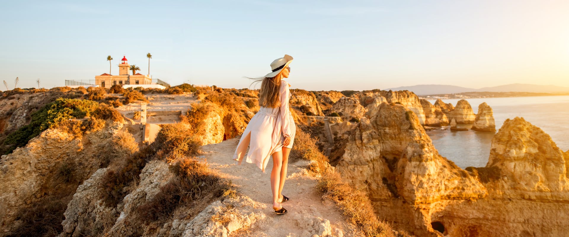 A woman walks along the coastline in the Algarve.