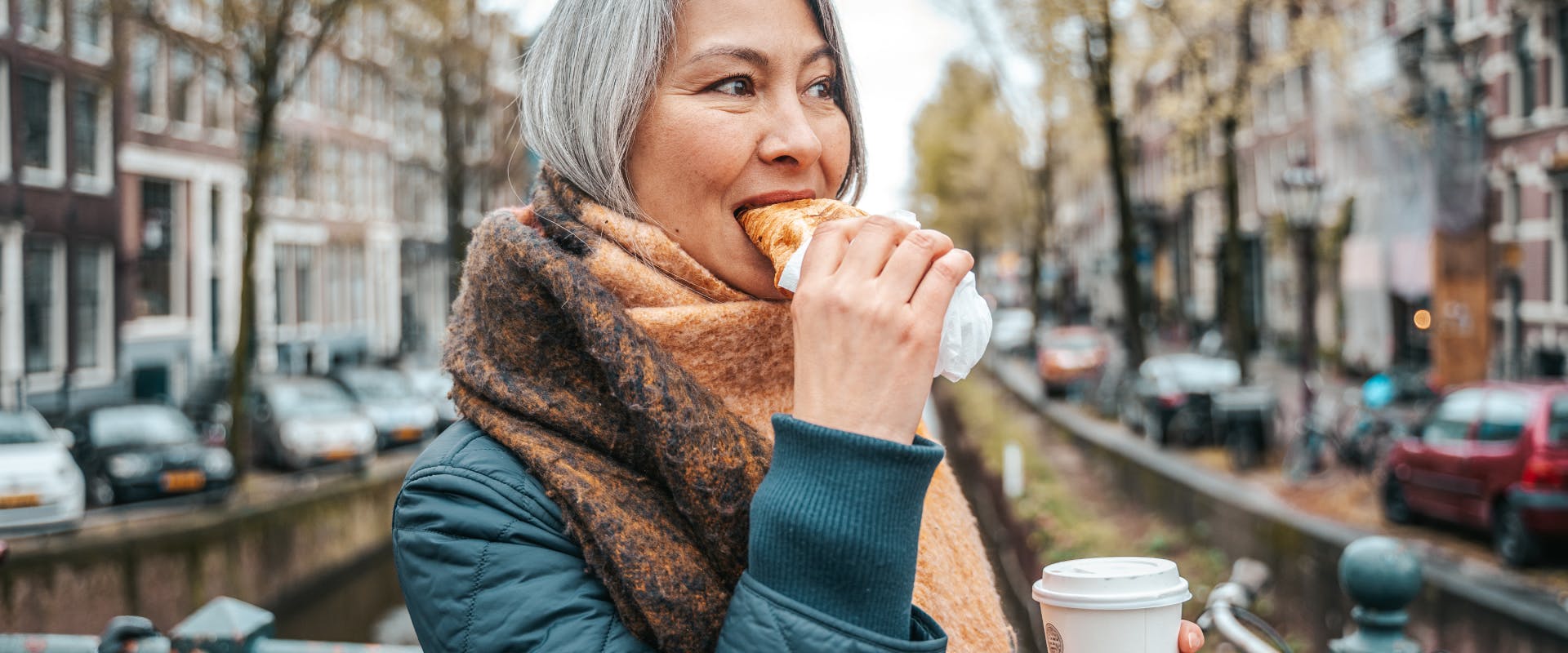 A woman eats a pastry in Amsterdam.