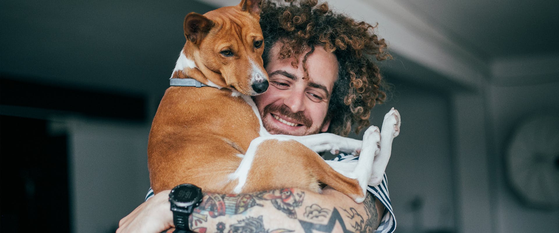 A smiling man holding a dog in his arms