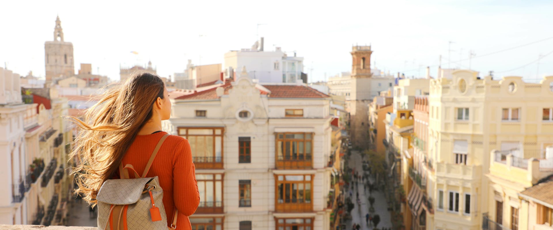 A solo female traveler looks out over rooftops in Spain.
