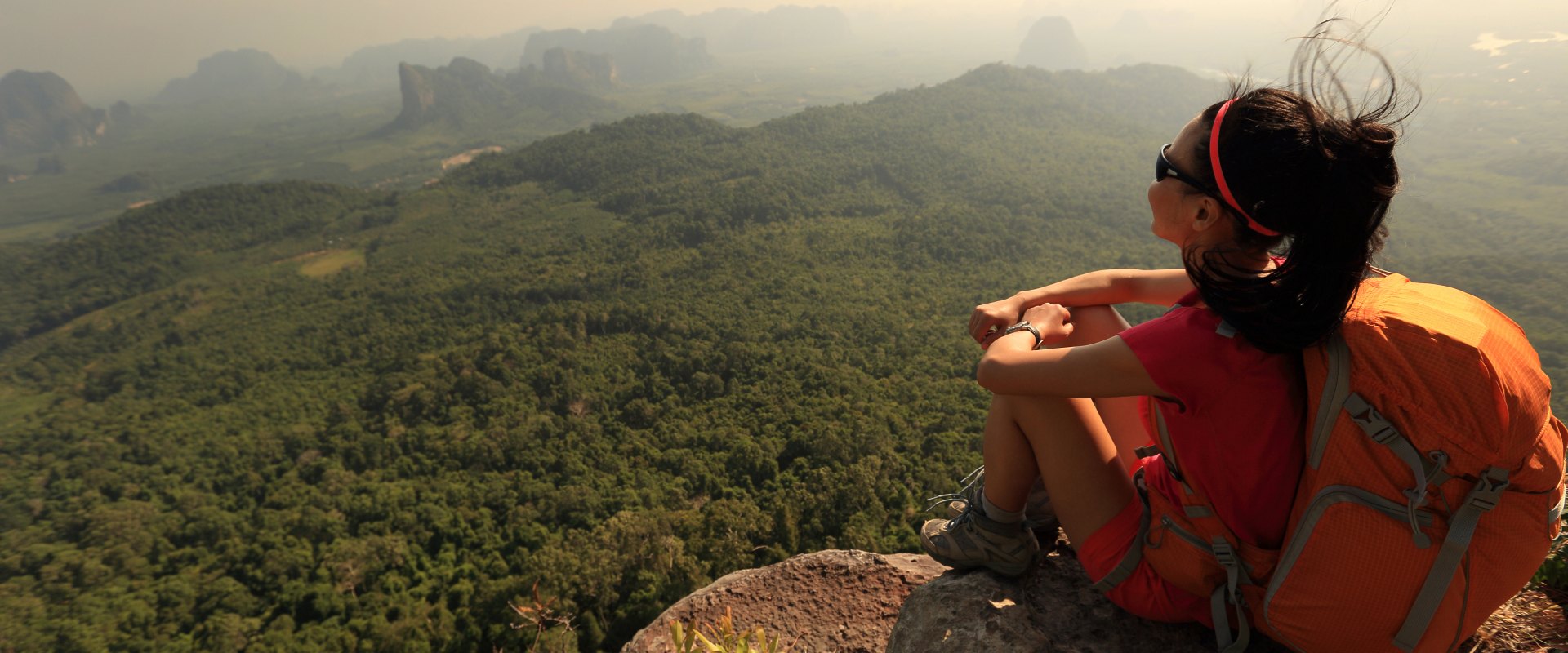A woman sits at the top of a mountain.