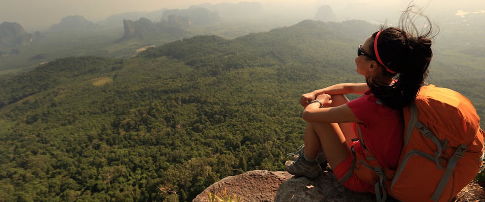 A woman sits at the top of a mountain.
