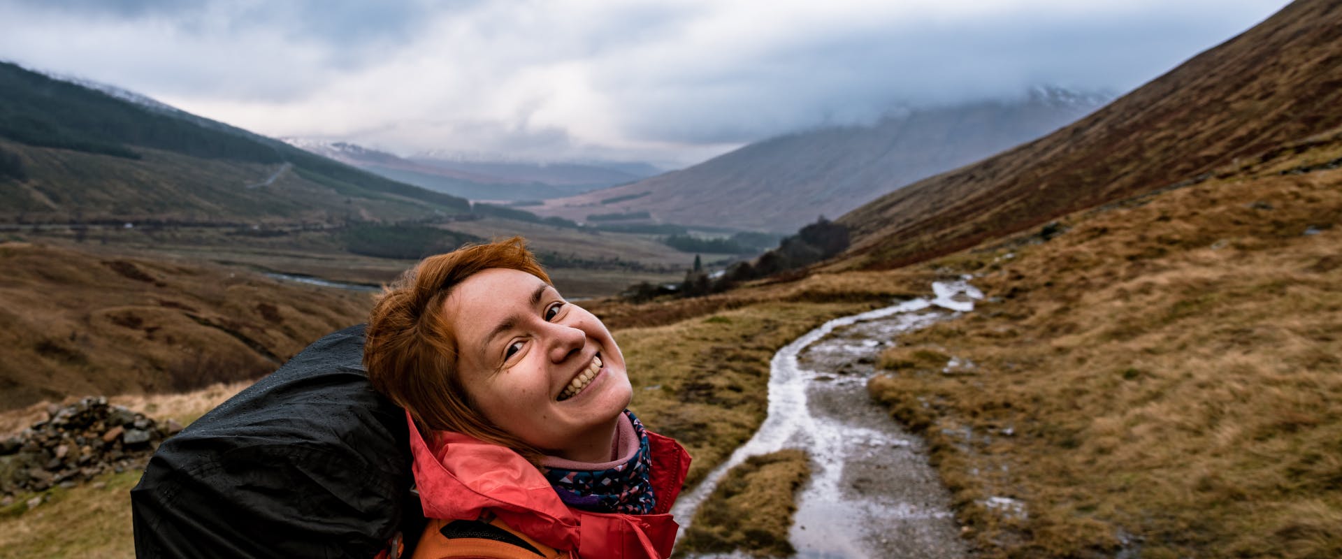 a solo female traveler in scotland walking through the scottish highlands