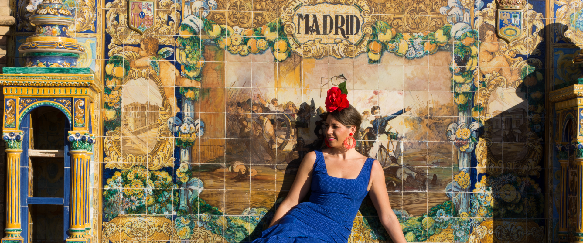 A flamenco dancer sits in front of a tile wall.