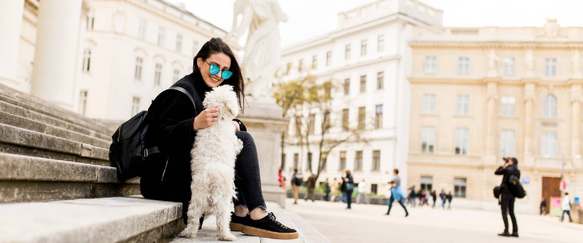 Girl sitting on stairs with her pet dog after walk in the city