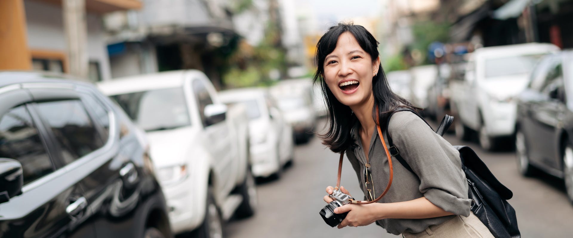 A female solo traveler laughs as she takes a photo.