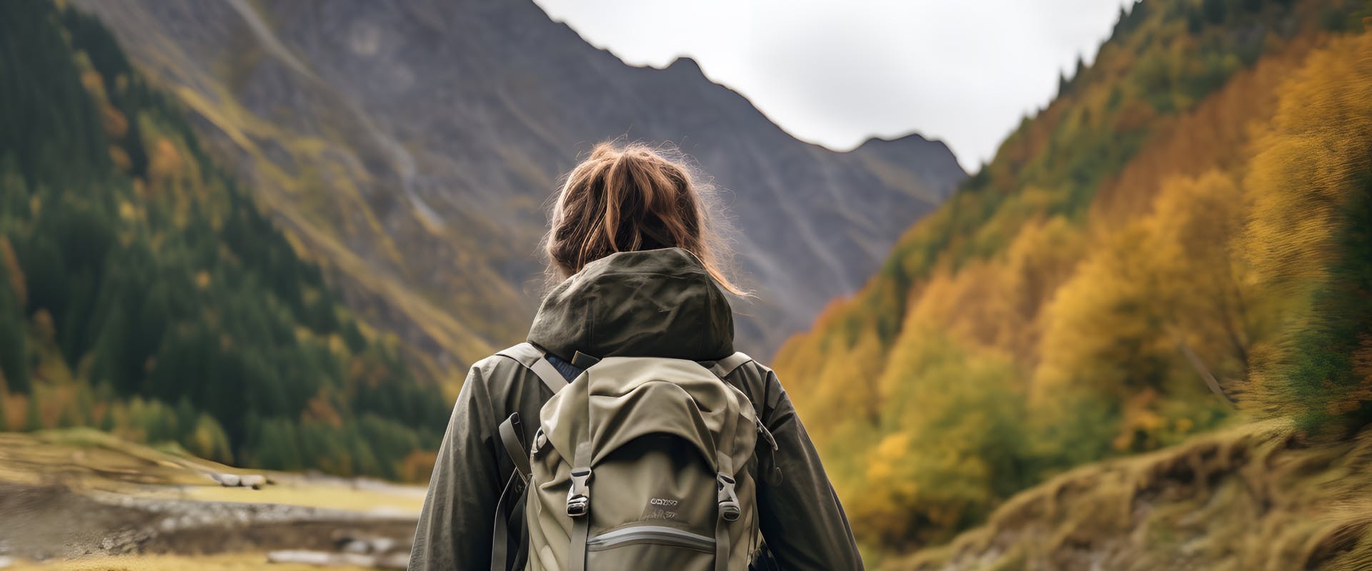 solo female traveler with solo camping gear backpack looking at a mountain valley