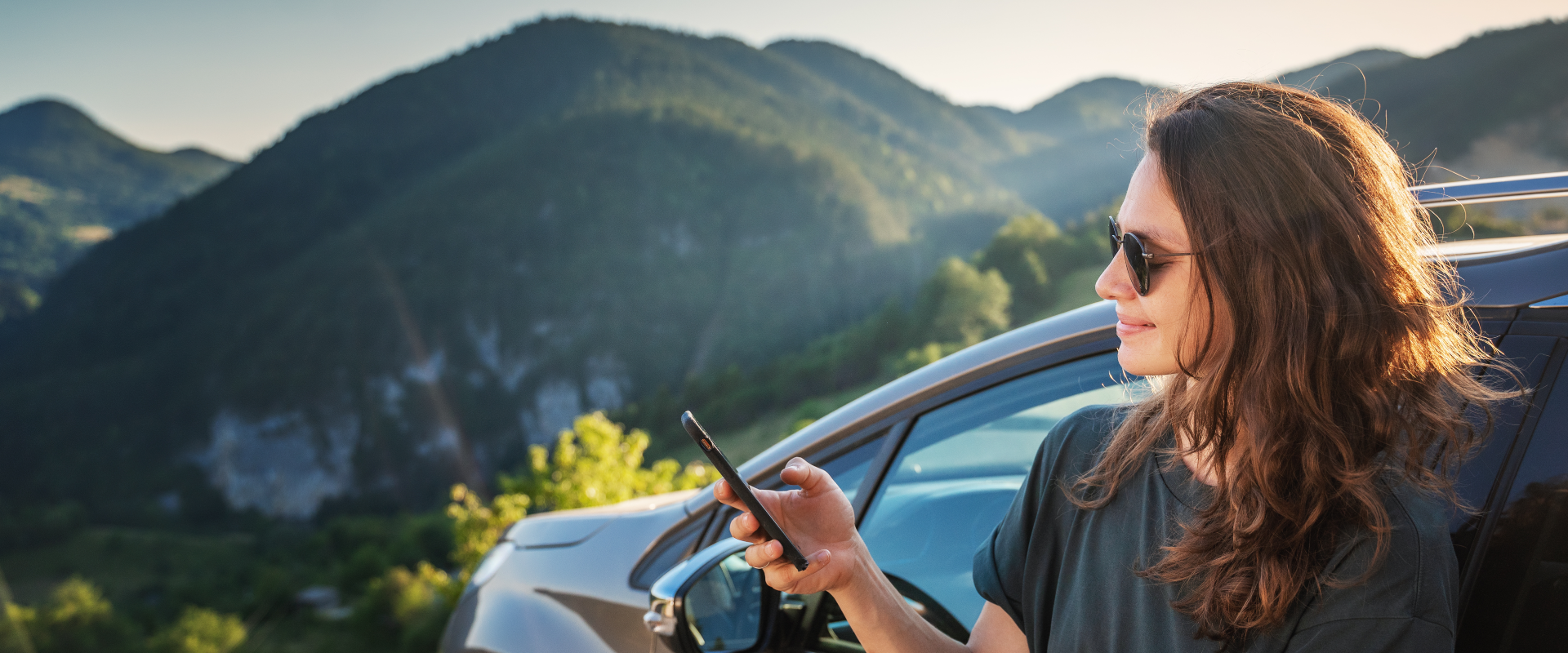 solo female traveler looking at her phone next to a mountainous view