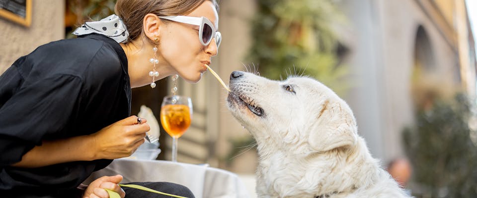 A woman eating spaghetti with her dog