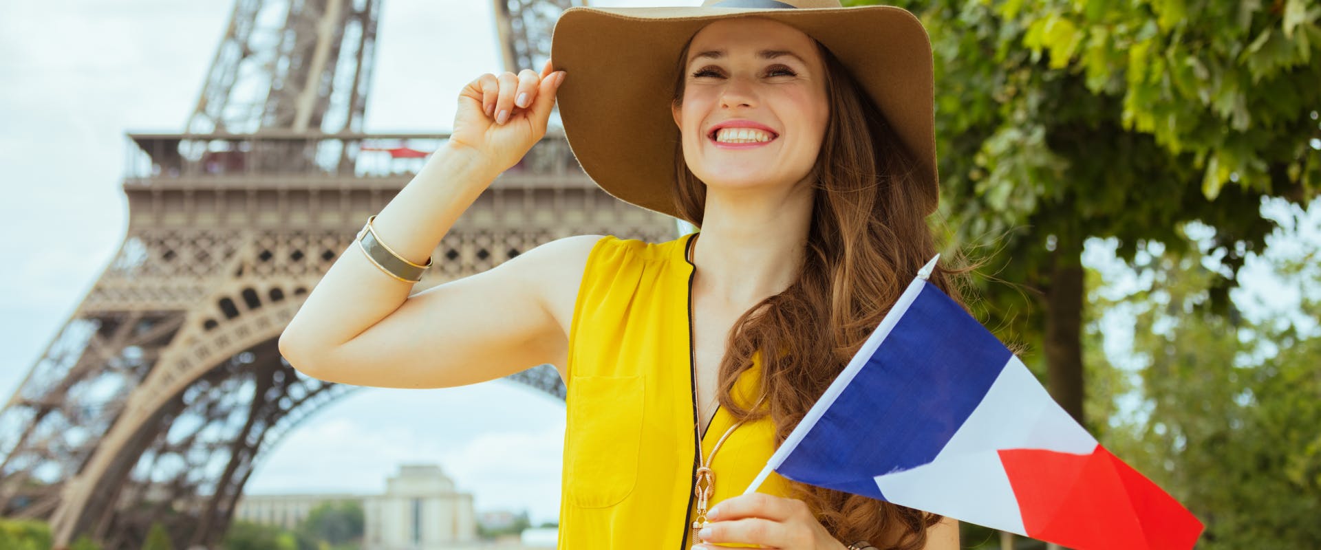 a solo female traveler in Paris holding a French flag with the Eiffel tower in the background