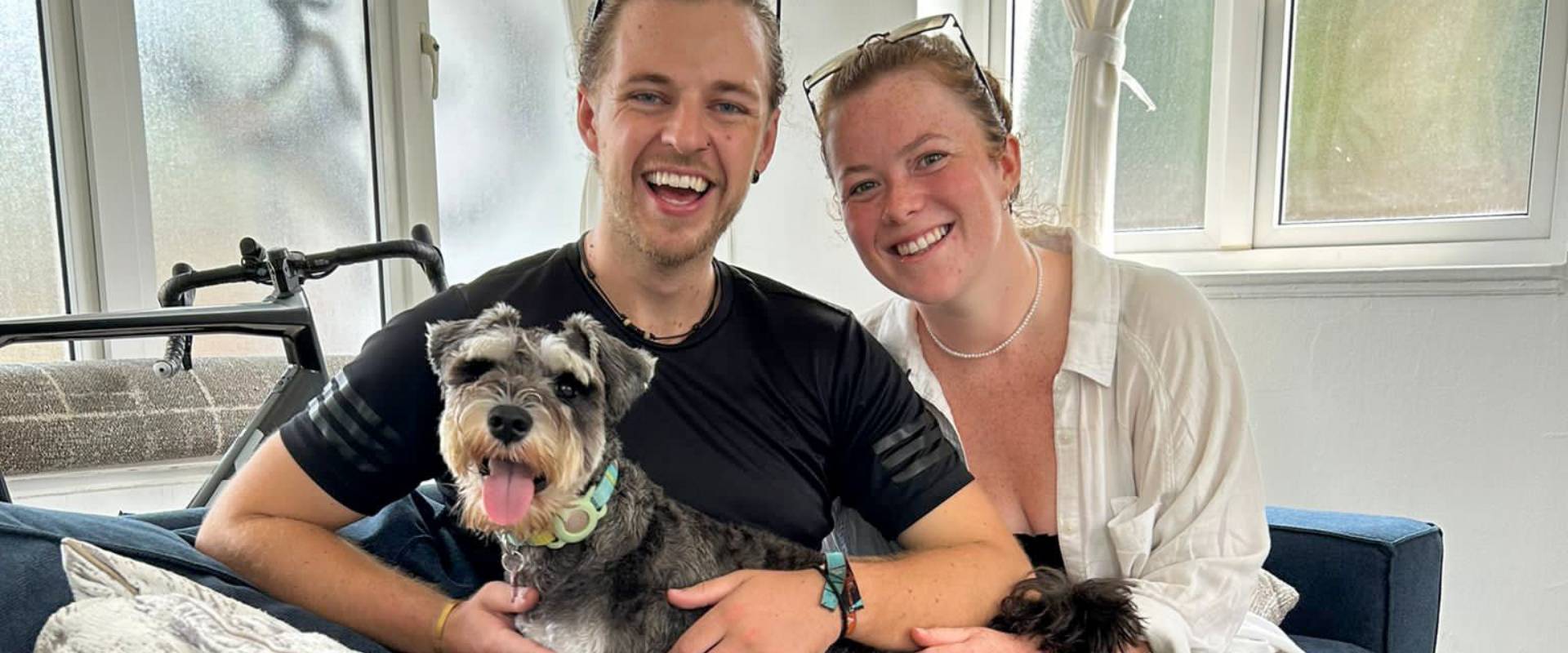 eion and aisling cuddling a miniature schnauzer on a coach whilst on a pet sit