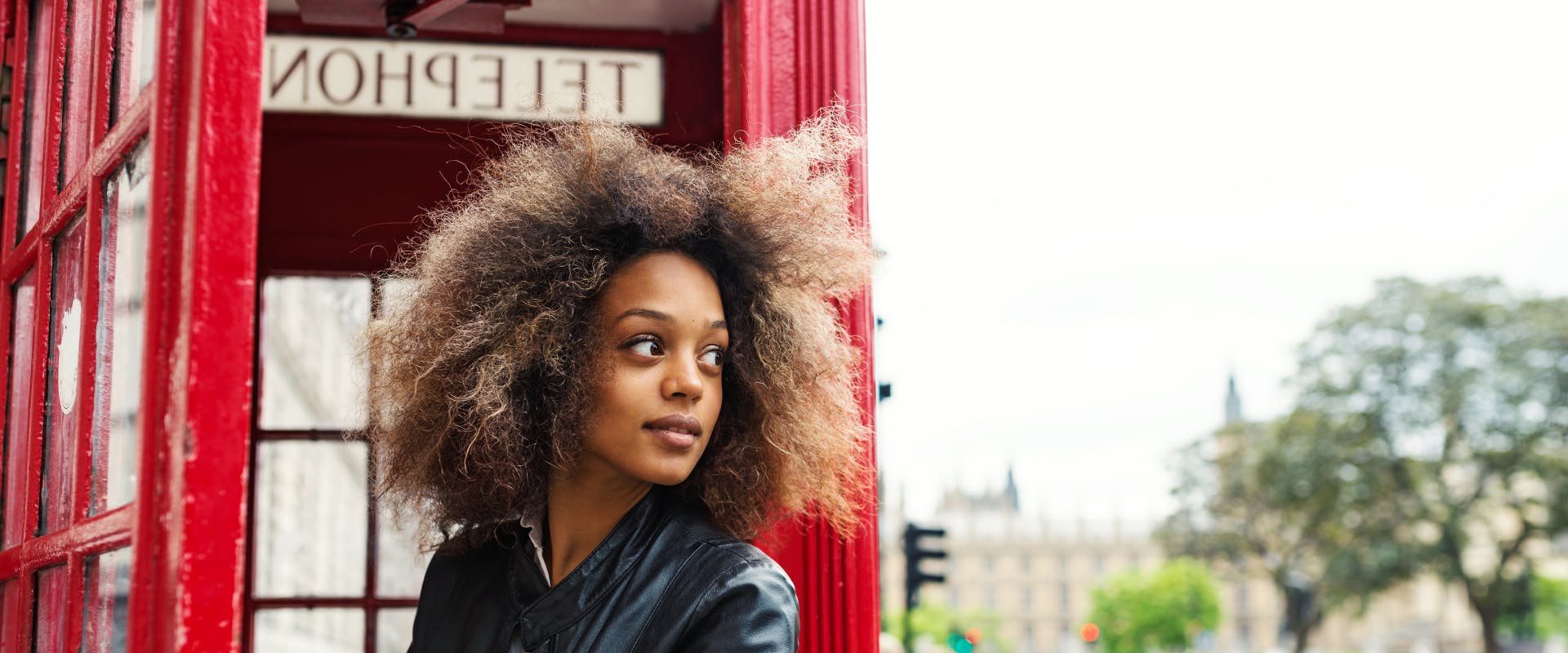 A woman walks out of a phone box.