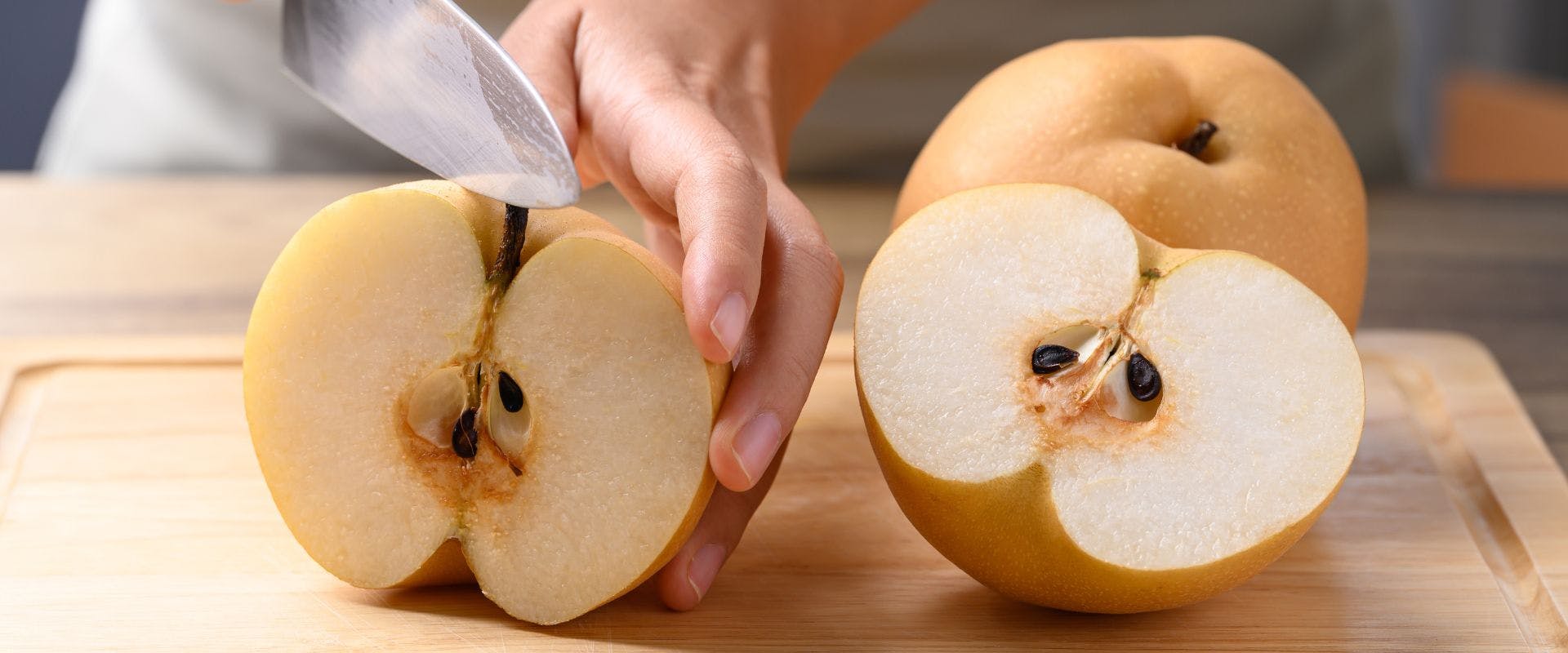 Asian pear being sliced on wooden board