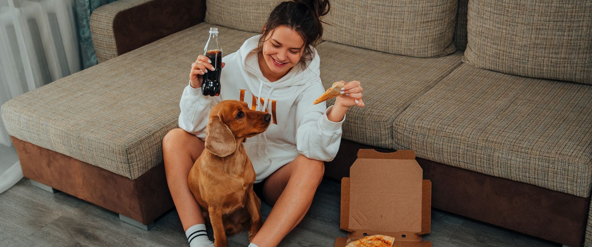 Person eating pizza and drinking cola with a Spaniel dog