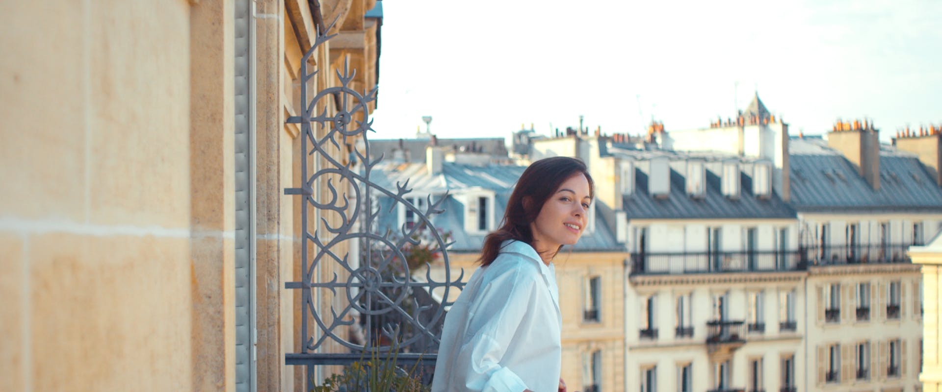A woman leans off a balcony in Paris.