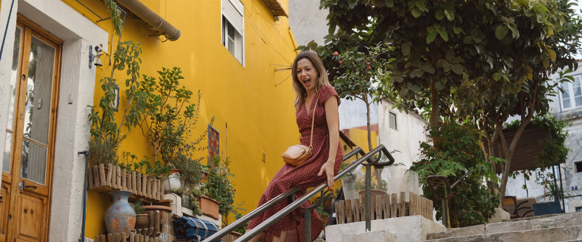 A solo female traveler slides down a banister in Lisbon.