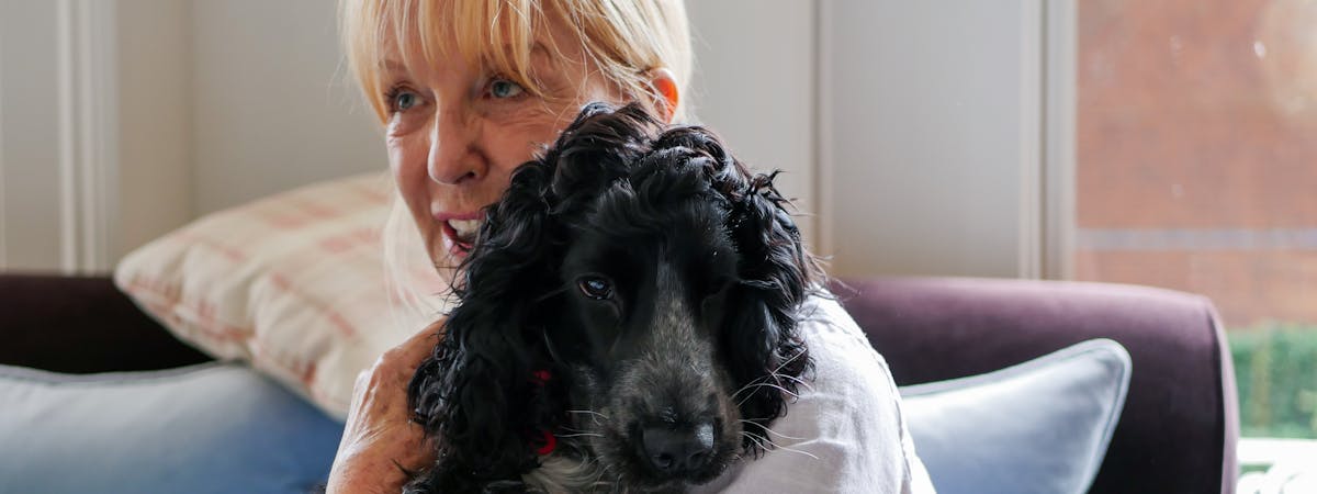 A blonde woman holding a small black dog