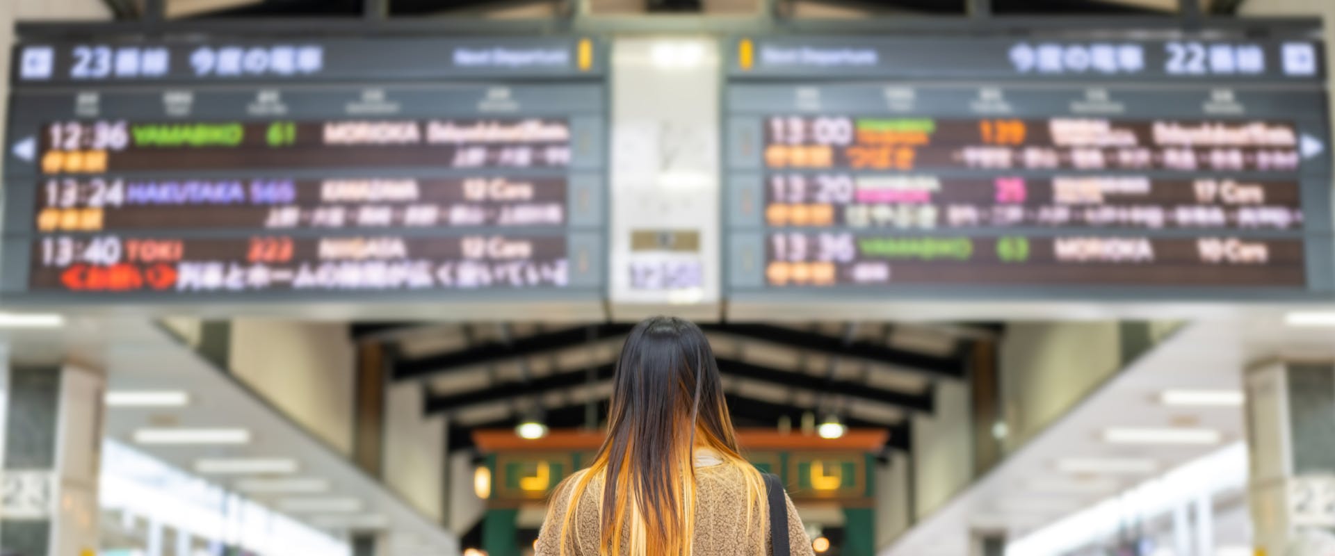 solo female traveler looking at a train timetable in Japanese