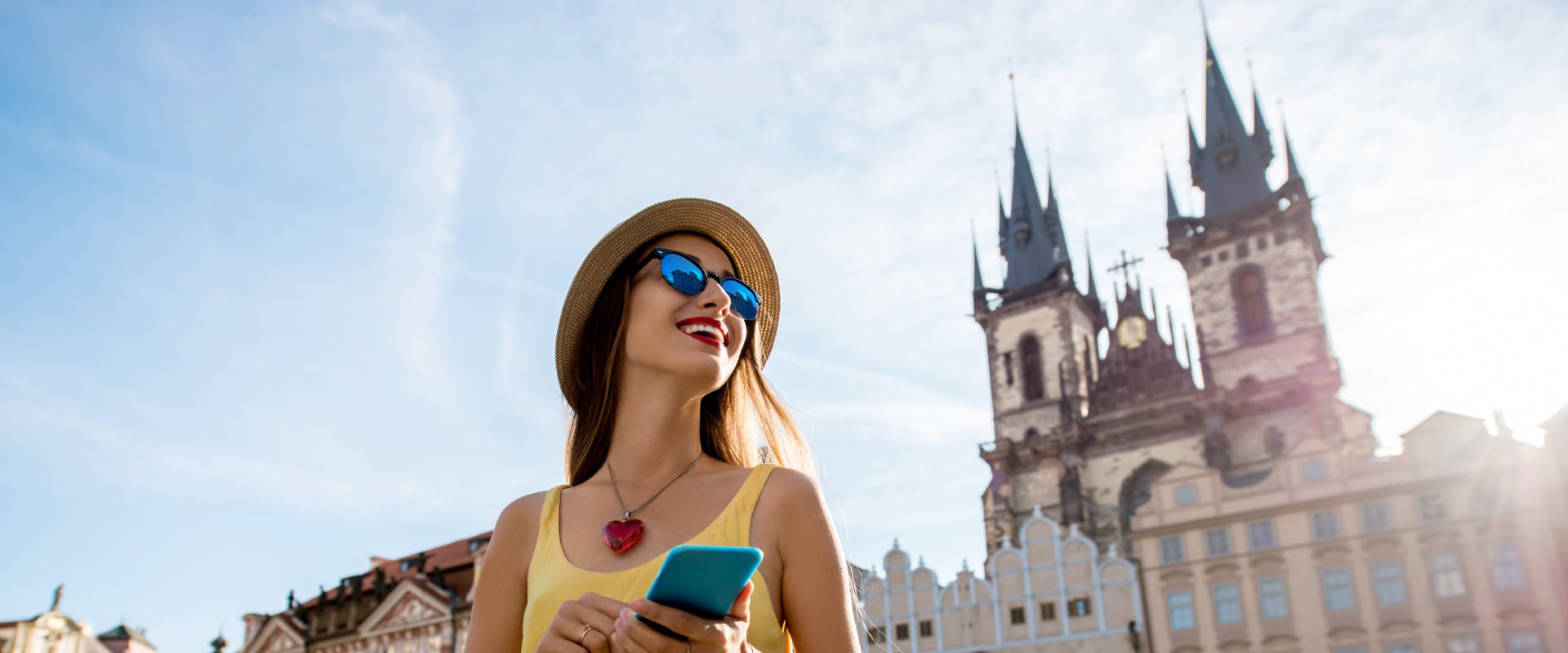 solo female traveler holding her phone whilst walking through Prague's town square
