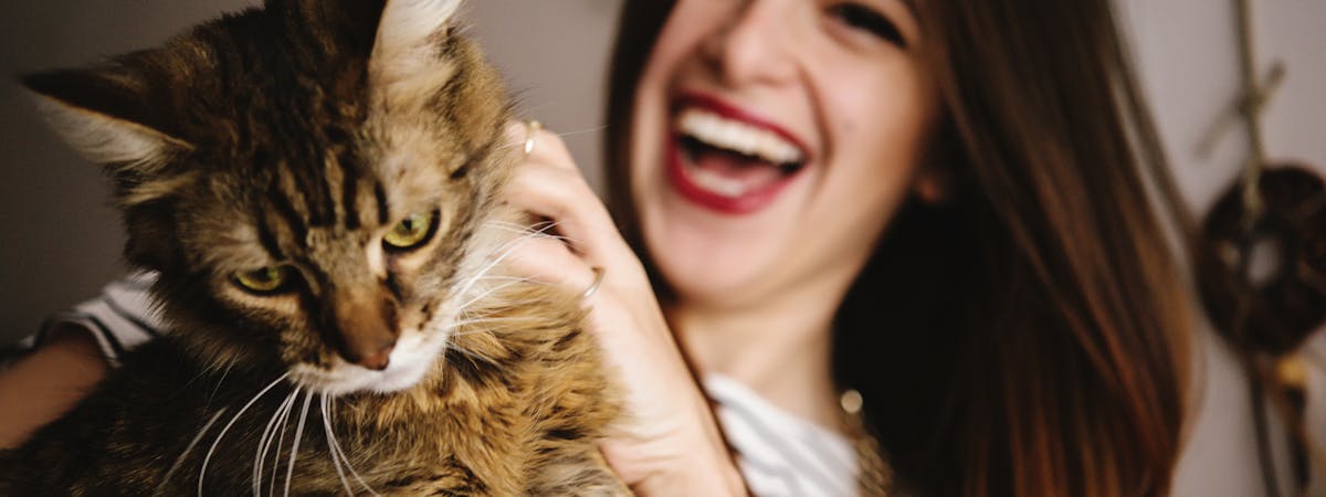 Woman laughing while holding a cat