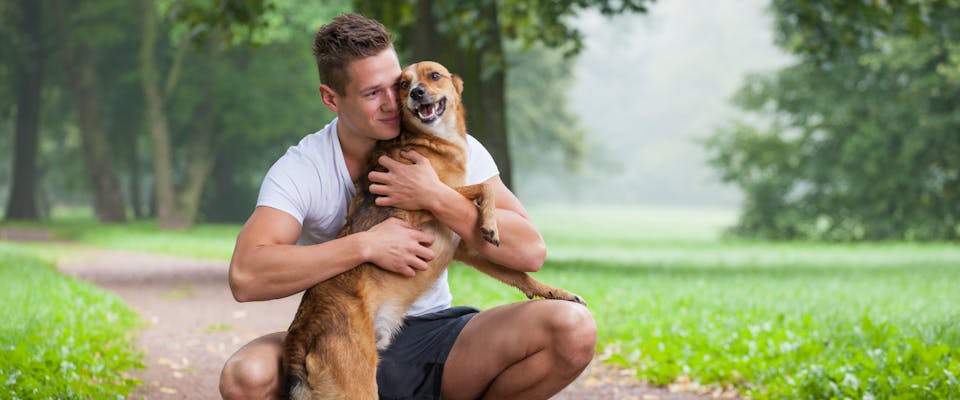 Man hugging a dog in the park.