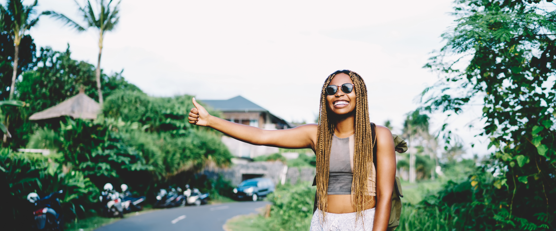 A solo female traveler sticks out her thumb for a ride.