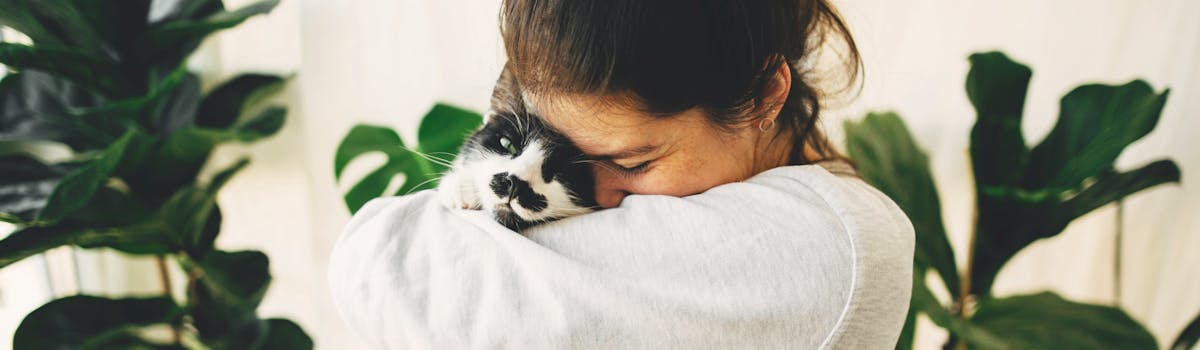 A woman cuddling a black and white cat