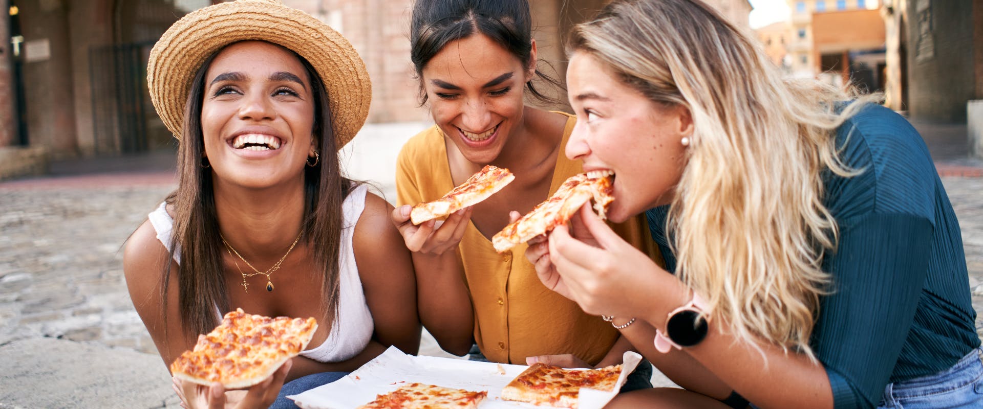 Three girls eating pizza in Rome.