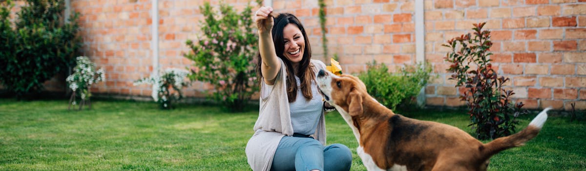 A woman playing with a dog in a garden