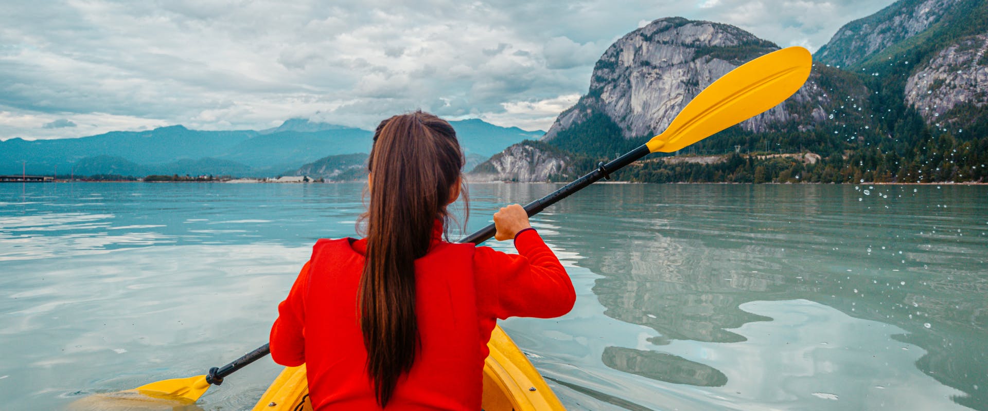A woman kayaks across a lake.