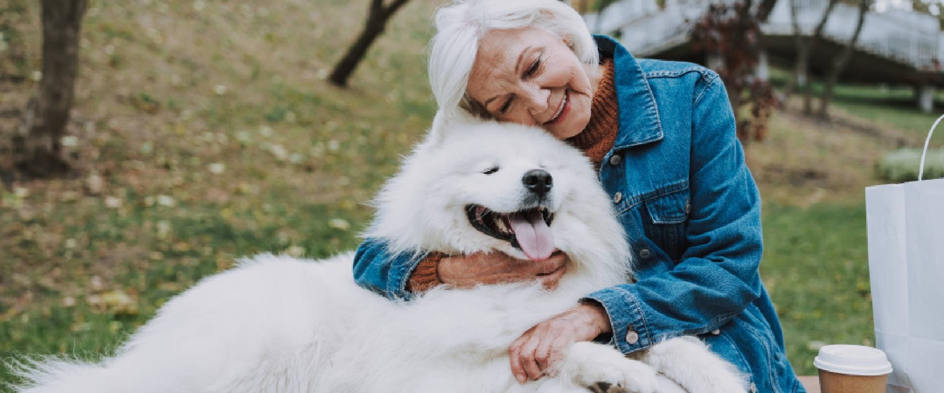 Woman cuddling a medium-sized white fluffy dog