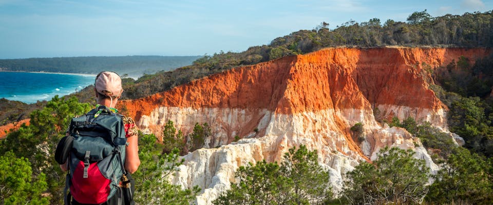 a hiker looking at a red cliff face in australia, solo female traveling