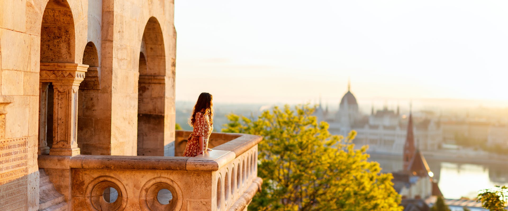 a solo female traveler looking at a view of the river danube and the hungarian parliamentary building
