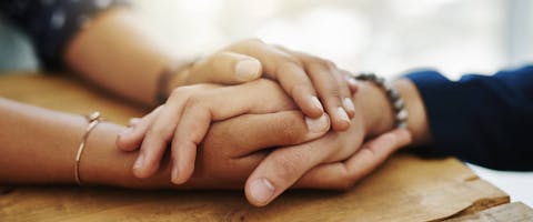 Two pet parents holding hands in comfort.