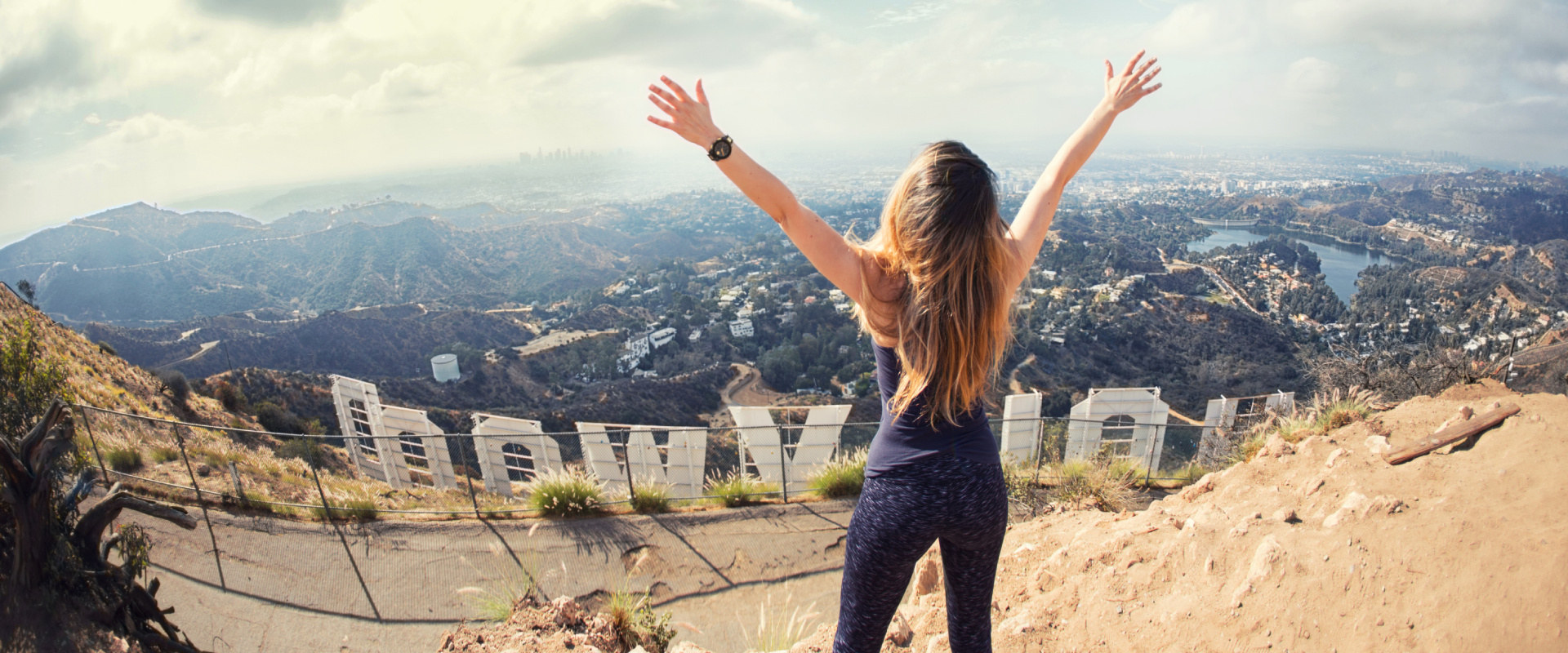 a solo female traveler standing above the Hollywood sign
