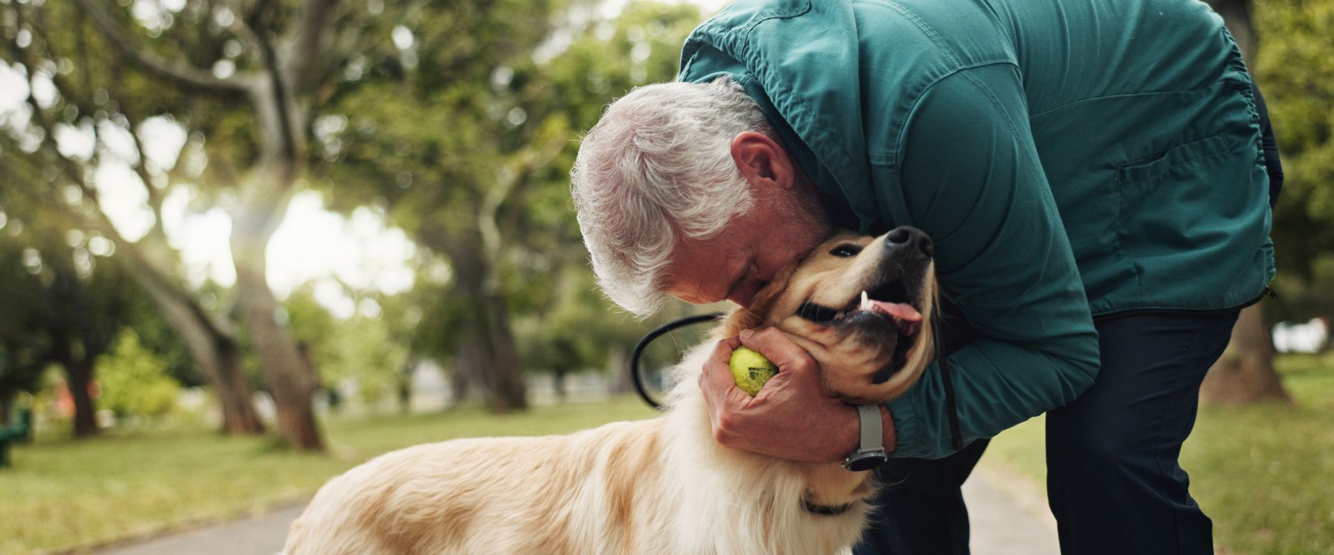 Man embracing a Golden Retriever in a dog park