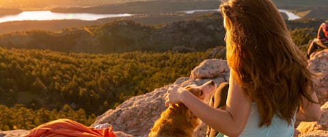 a dog and a woman watching a sunset on a rocky outcrop near Fort Collins