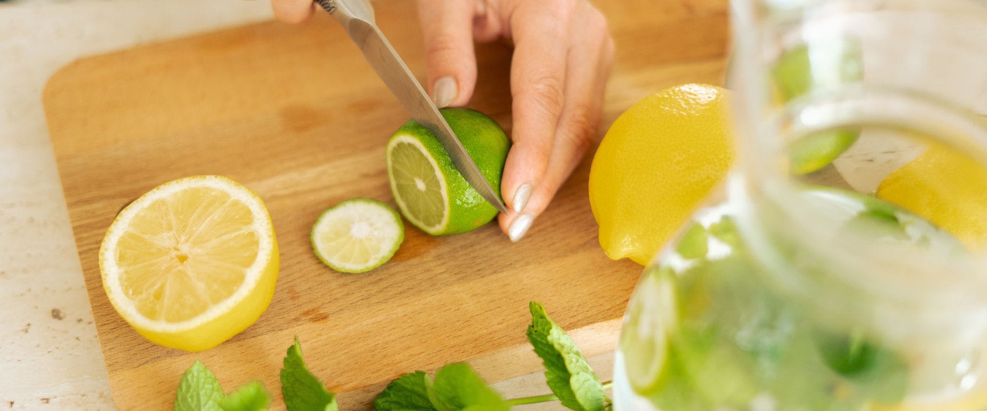 Limes being sliced on a wooden chopping board