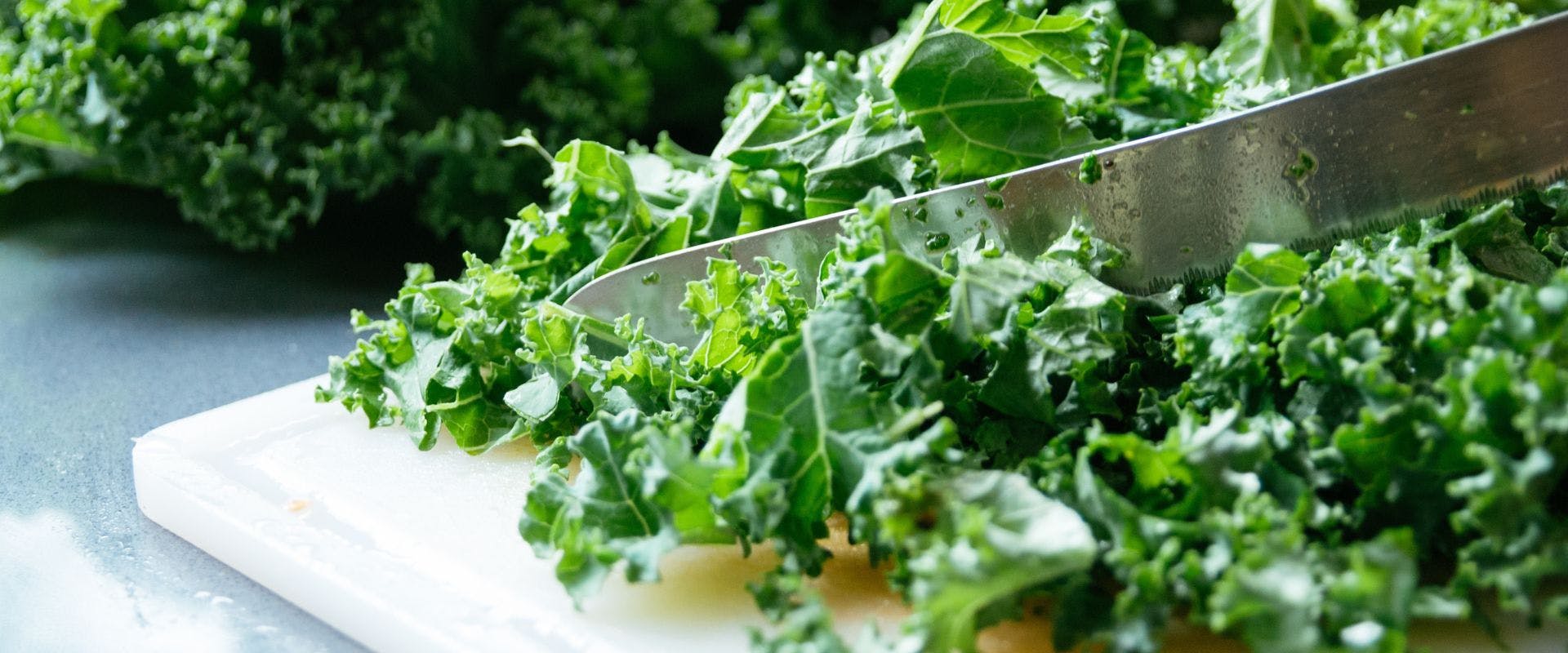 Kale being sliced on a chopping board