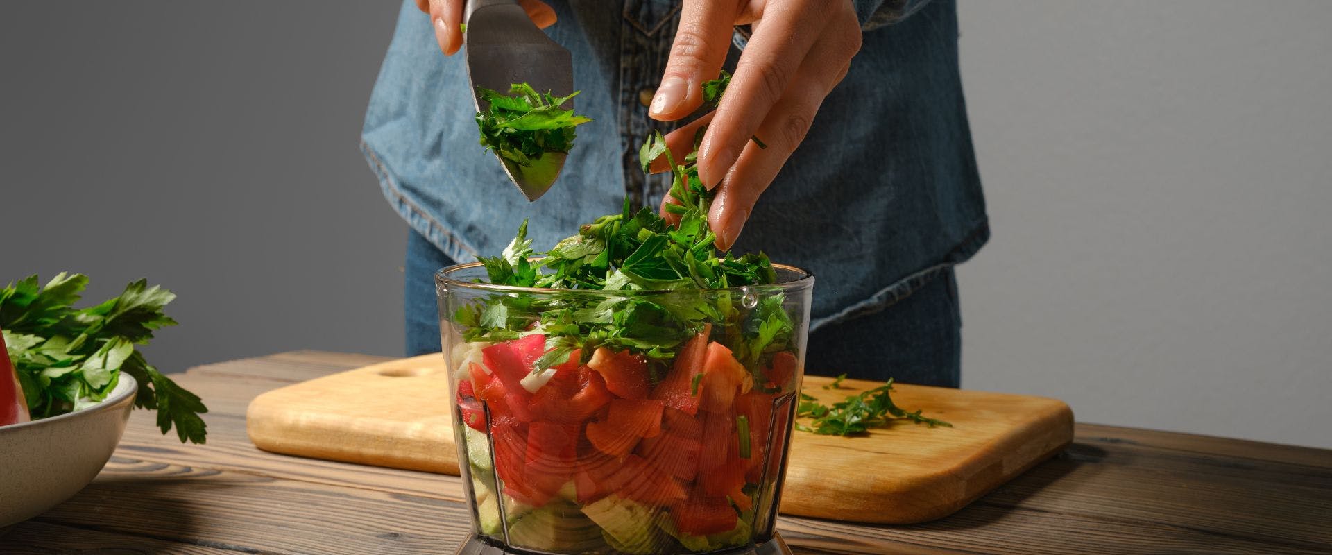 Cilantro being added into a blender with other salsa ingredients