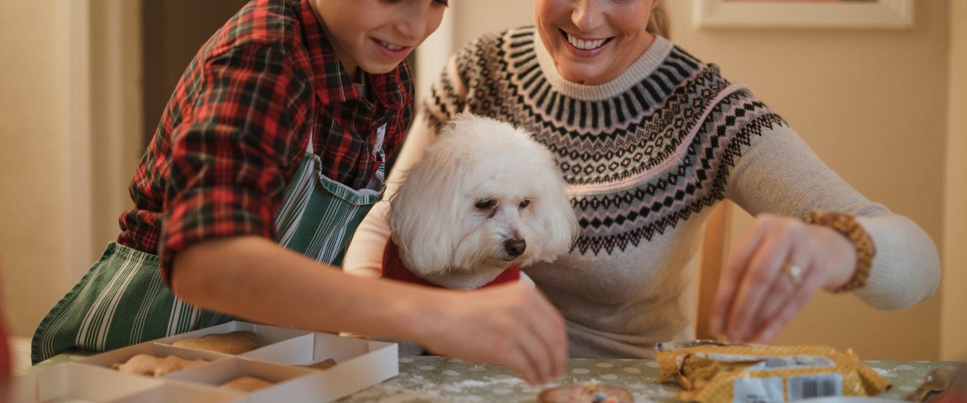 Mother and son baking with fluffy white dog
