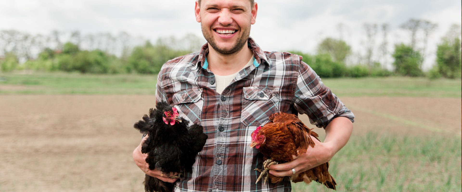 A chicken sitter holds two chickens.