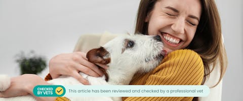 A woman smelling her puppy's breath. This article has been reviewed by a professional vet
