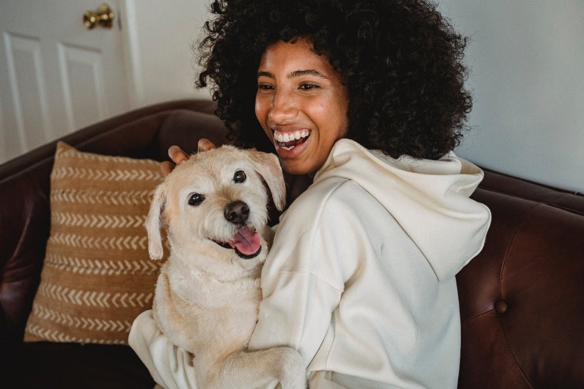 Person laughing and cuddling a dog