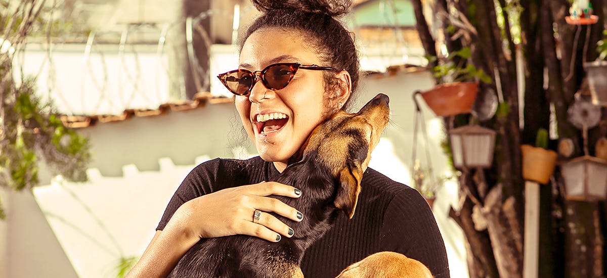 A smiling woman giving a small dog a hug