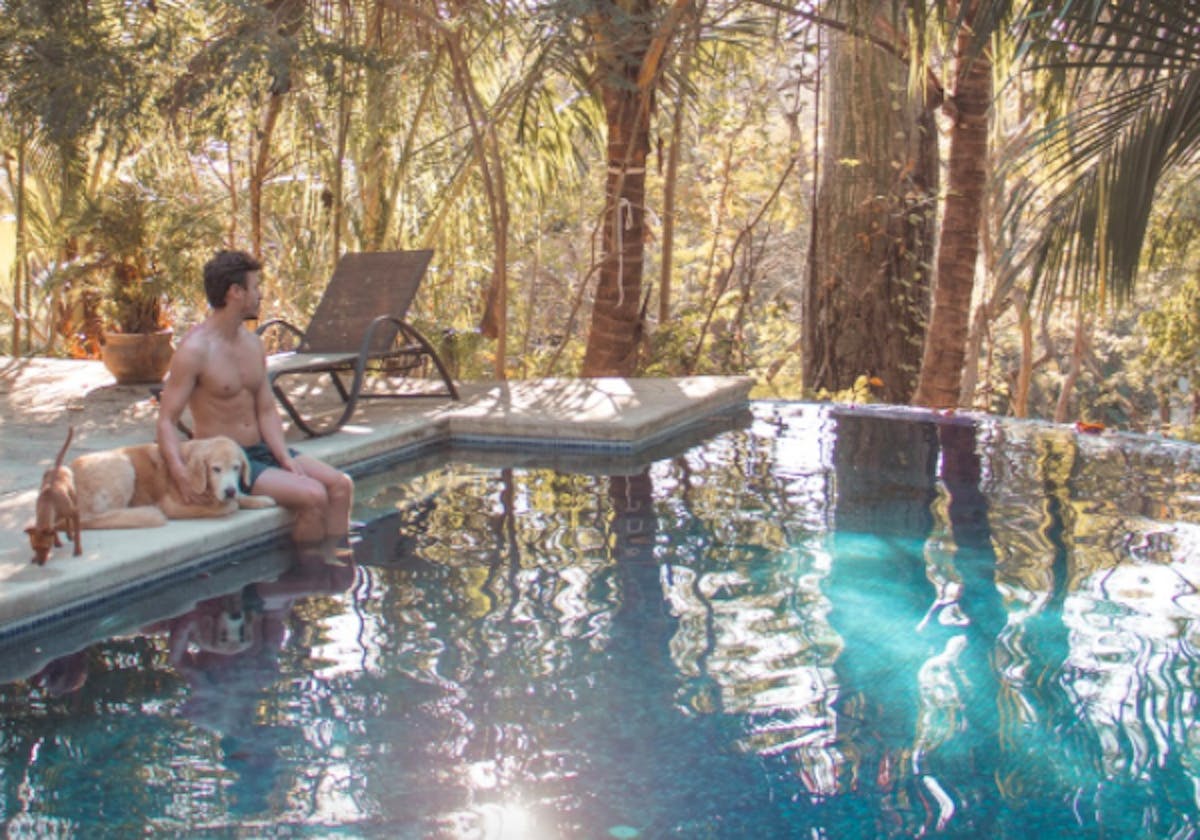 Man and dog sitting by a pool